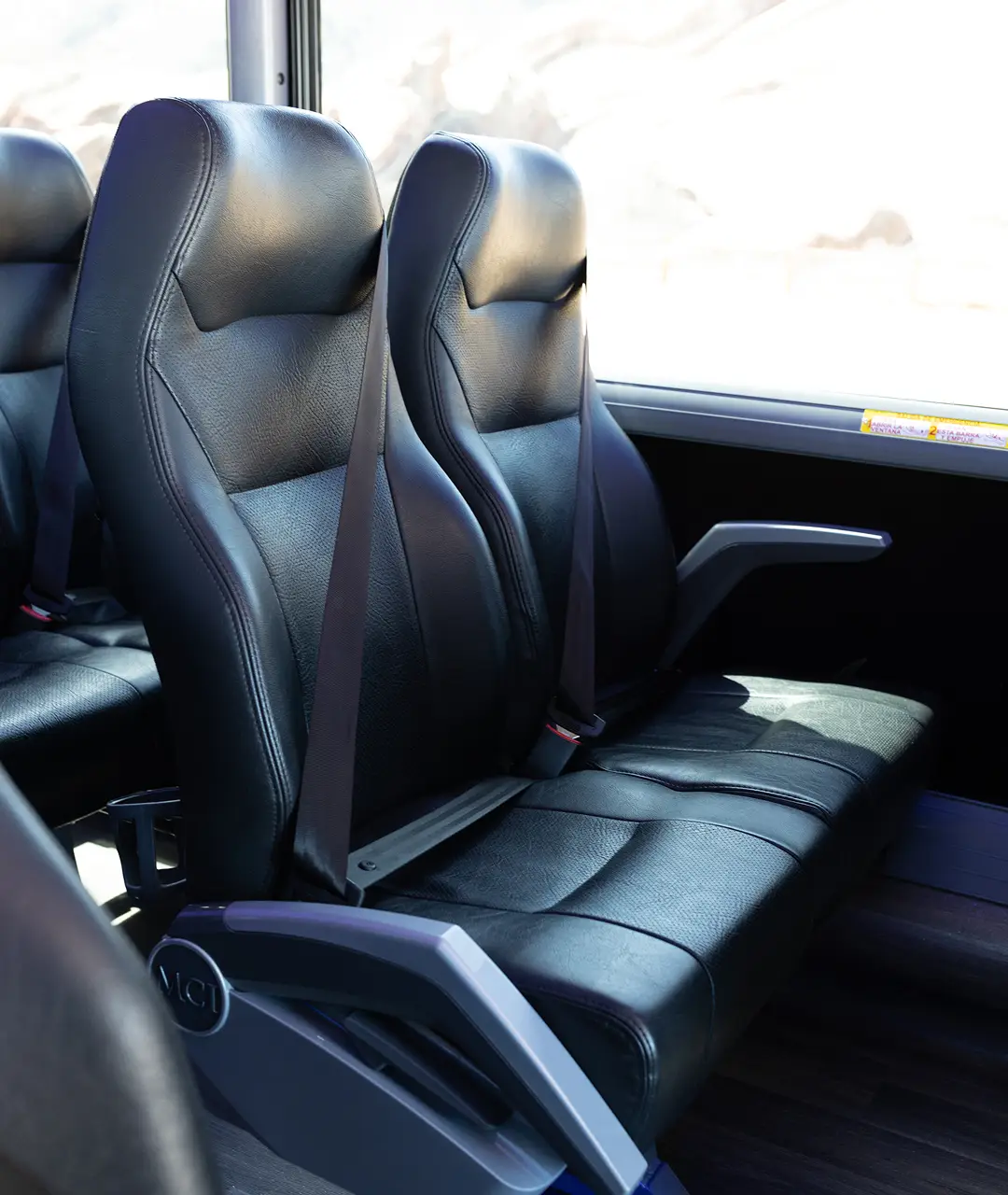 Interior view of black leather motorcoach seats with seat belts at Ace Express Coaches.