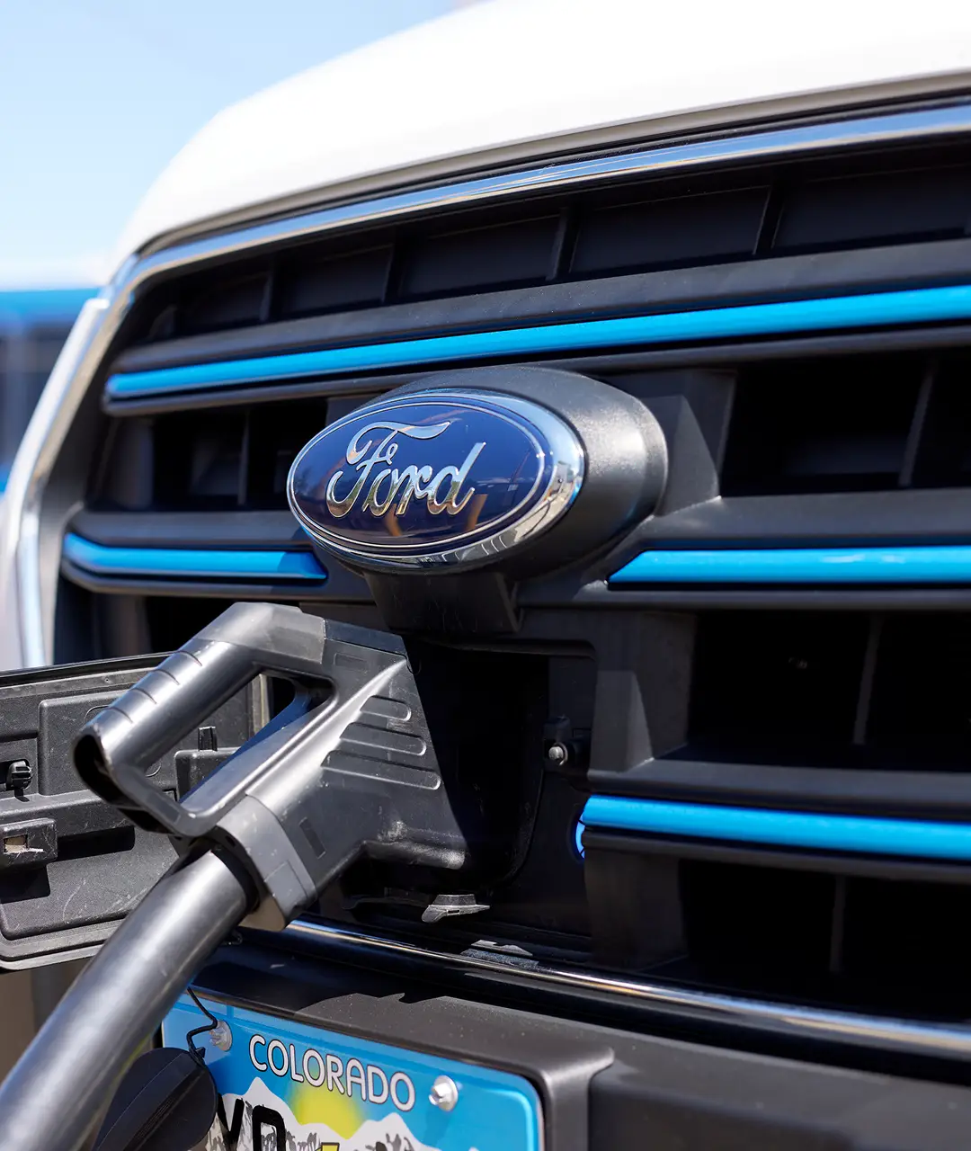 Close-up of Ford vehicle charging port with blue accents and Colorado license plate.