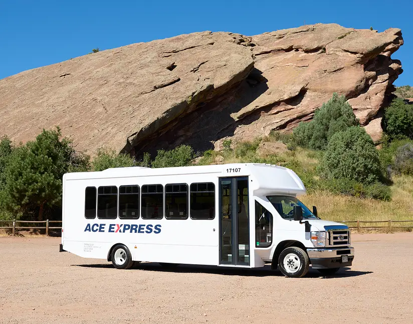 White Ace Express Coaches motorcoach parked outdoors with rocky landscape in the background.