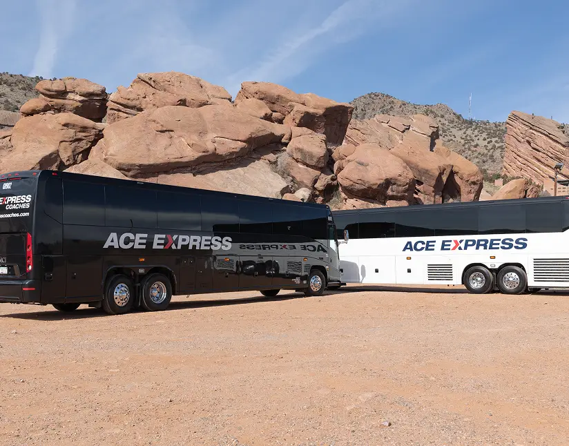 ACE EXPRESS Coaches parked in a desert with rocky formations in the background.