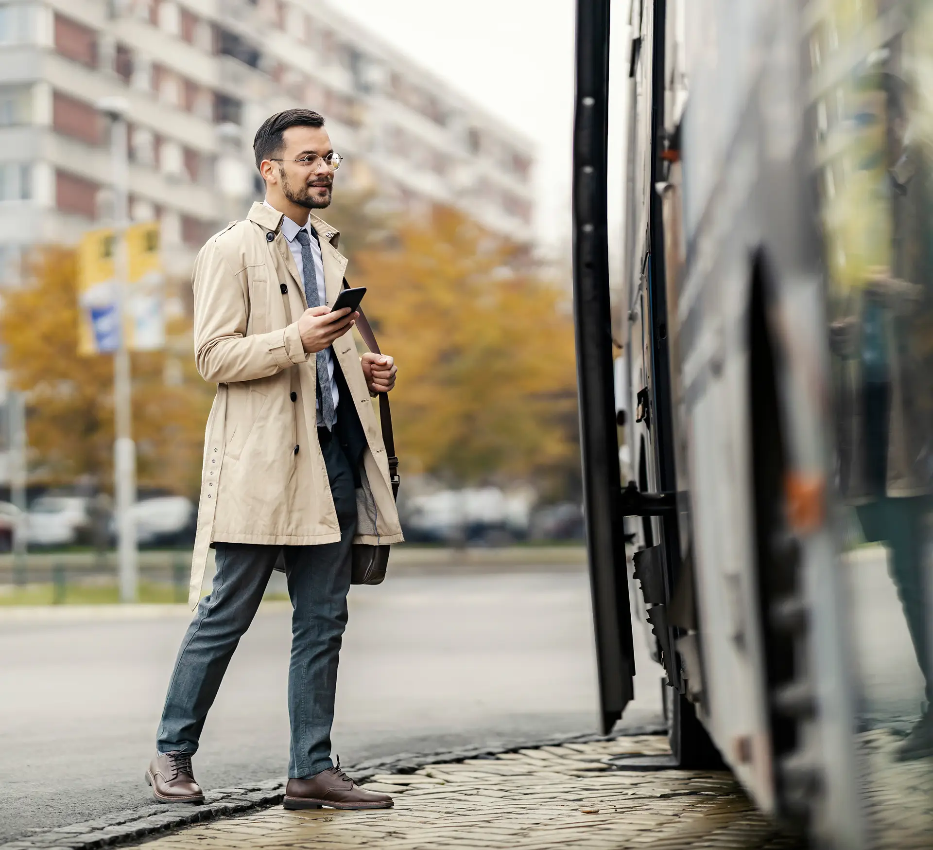 Passenger boarding a motorcoach using a mobile phone at a motorcoach stop.
