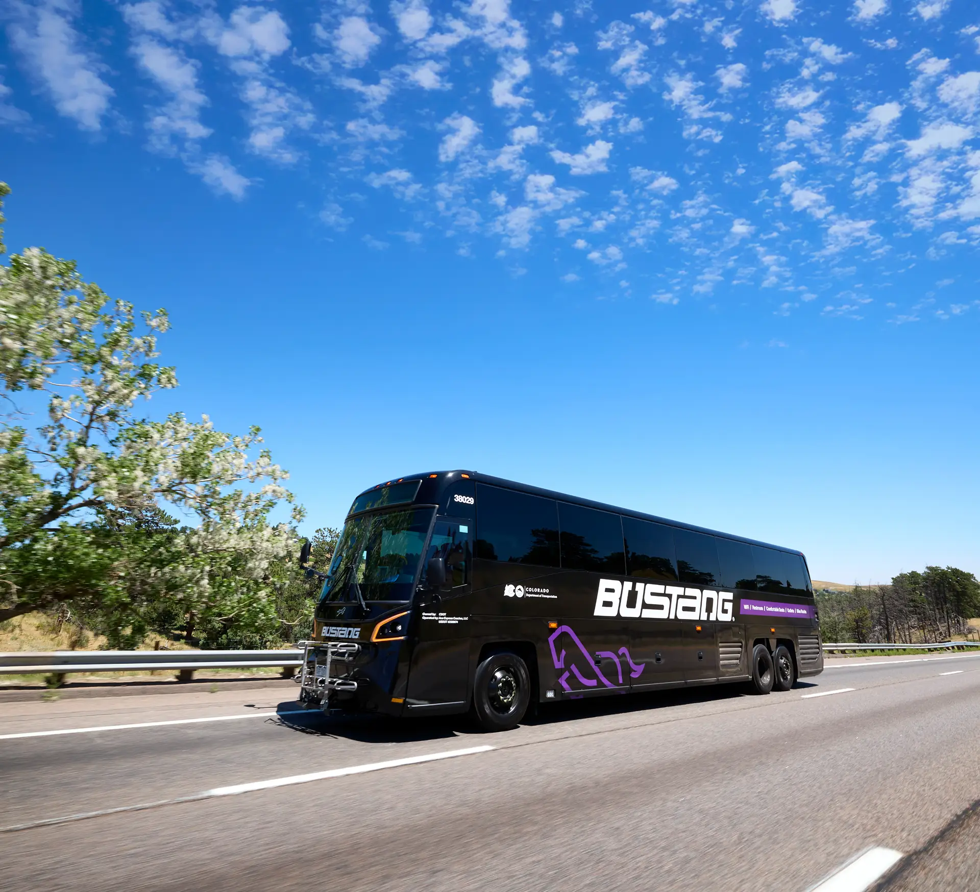 Modern black Bustang coach traveling on the highway with scenic background.