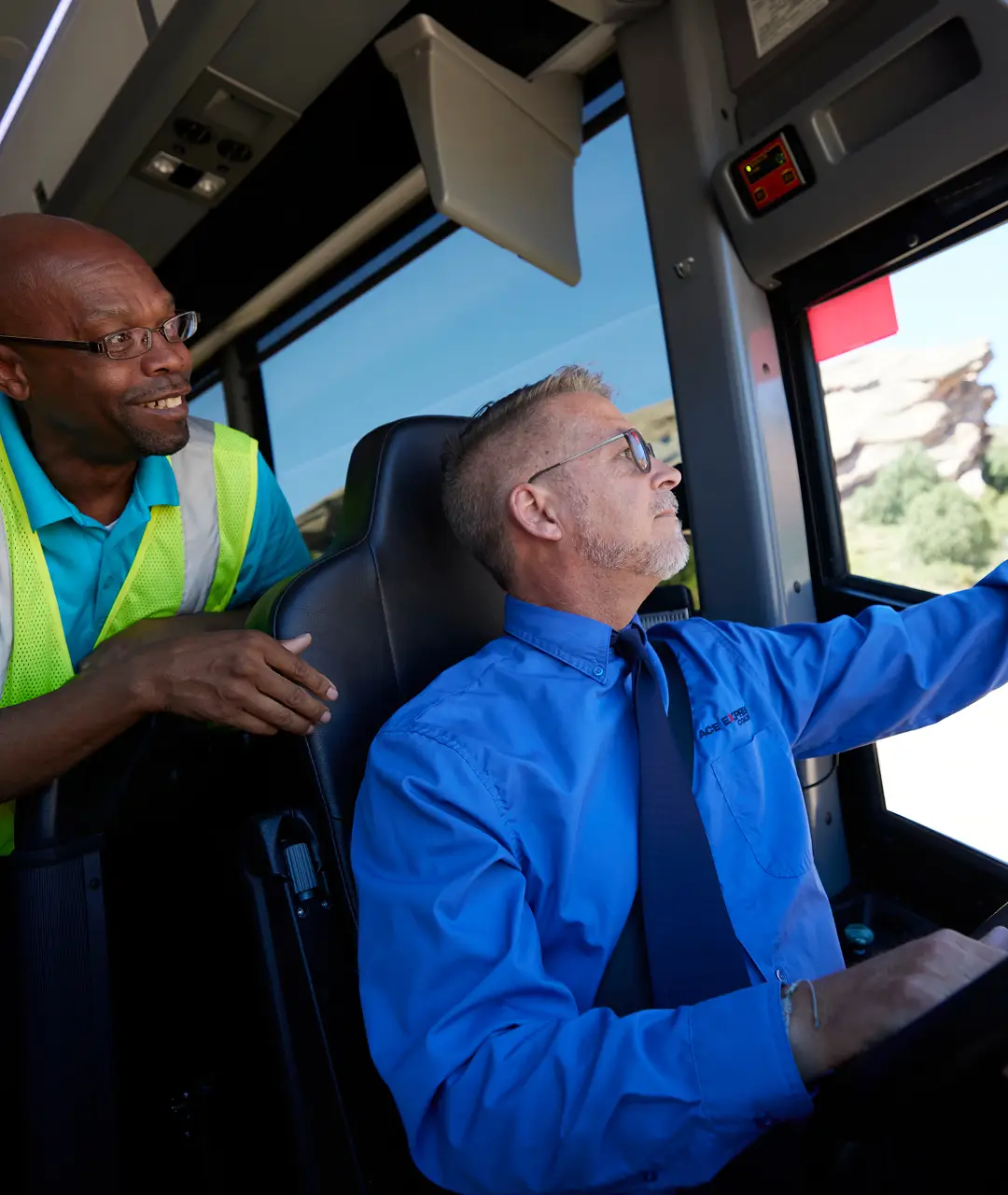 Motorcoach driver and passenger interacting inside the motorcoach, focusing on safety and service.