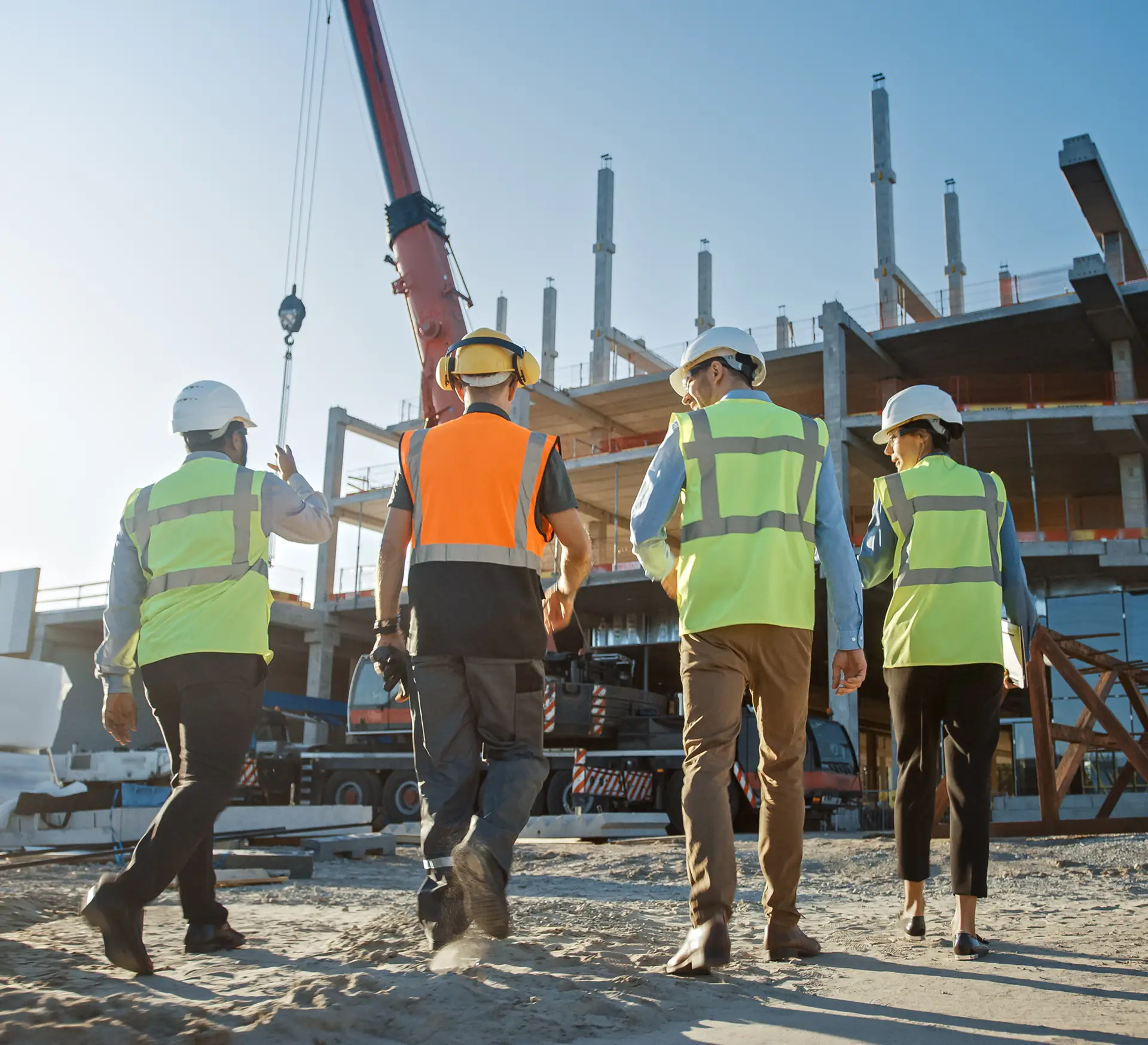 Construction site workers in safety gear walking towards a building under construction.