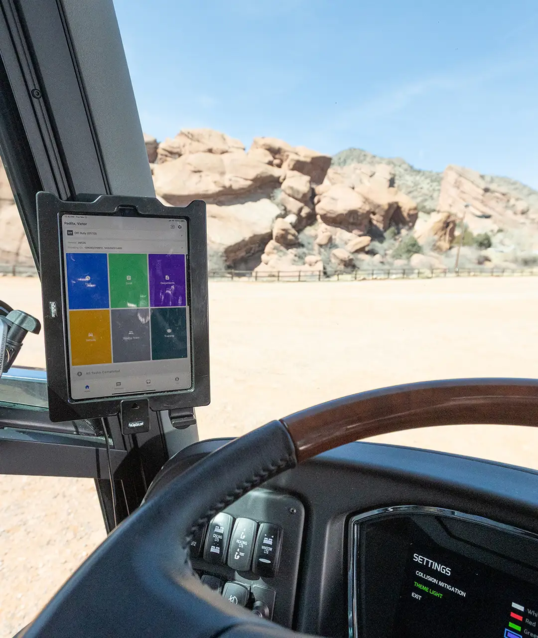 Interior view of a motorcoach cockpit showing digital controls and a scenic desert landscape outside.