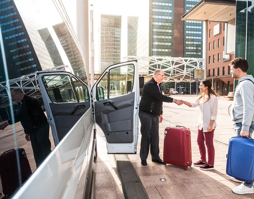 Business travelers greeting each other with luggage outside a city motorcoach.