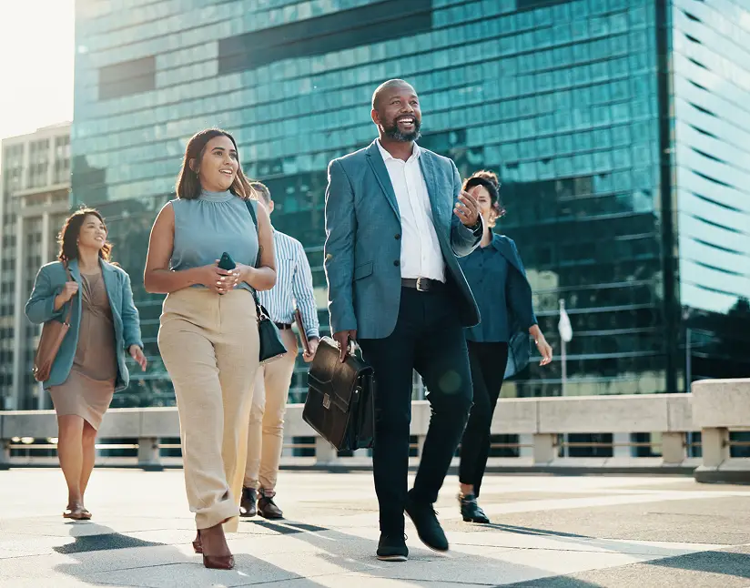 Business professionals walking outdoors in city, smiling and chatting.
