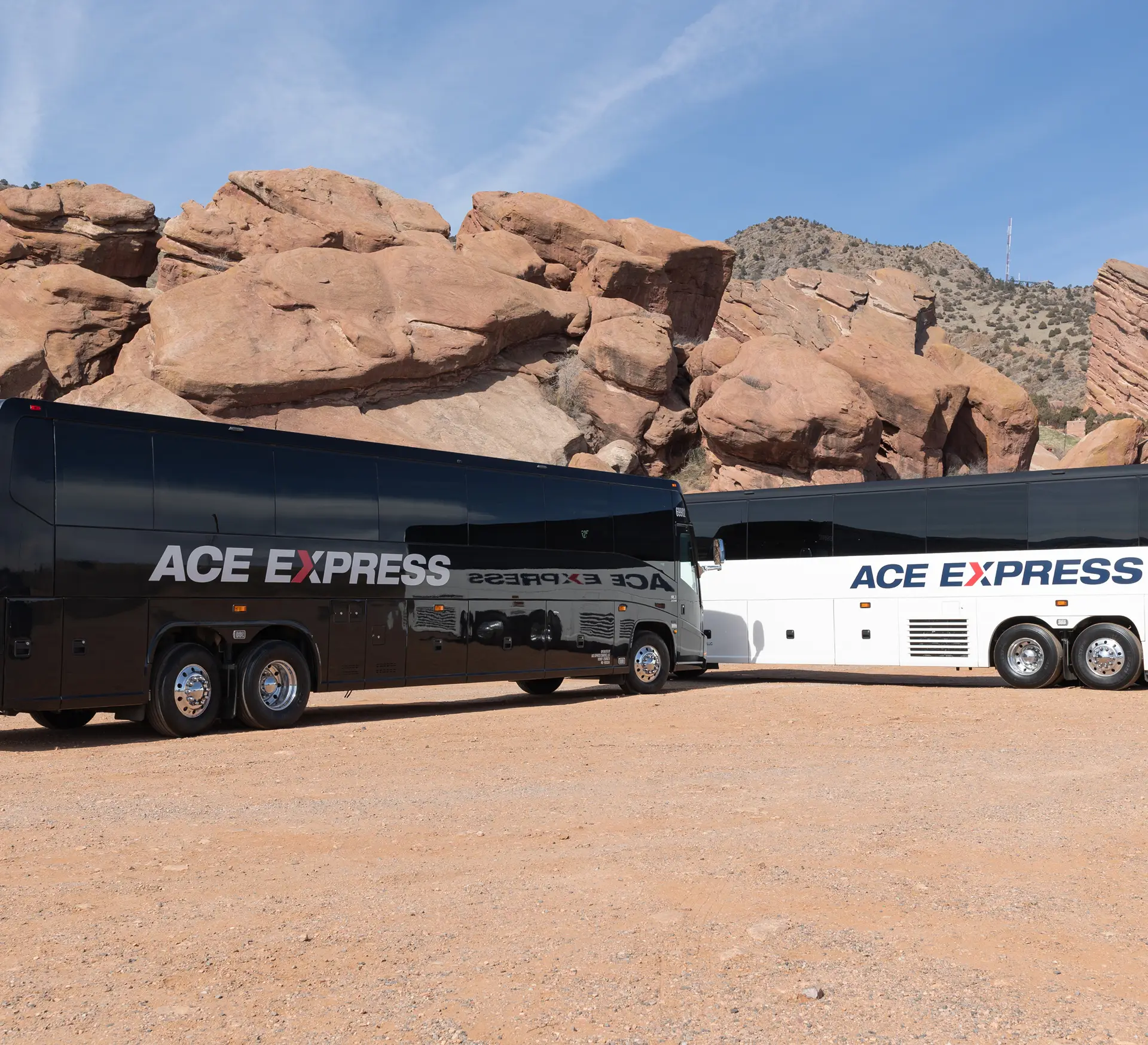 Image of Ace Express Coaches motorcoaches parked outdoors against a rocky background.