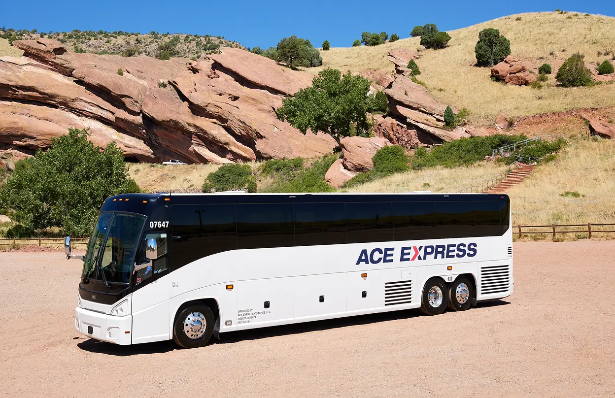 Motorcoach from Ace Express Coaches parked in scenic rocky landscape with hills and trees.
