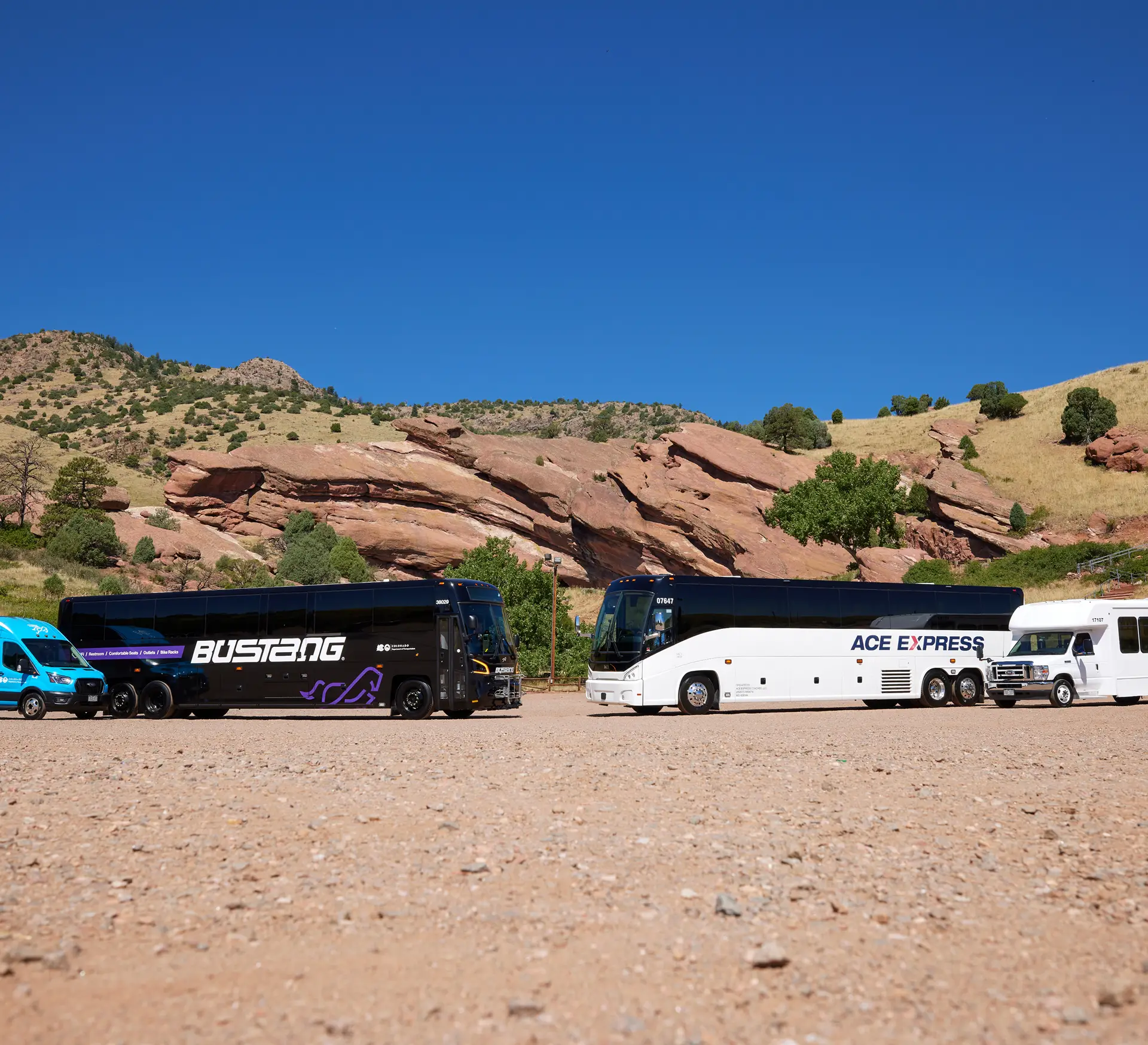 Image of Ace Express Coaches motorcoaches parked in a desert with rocky hills and clear blue sky.