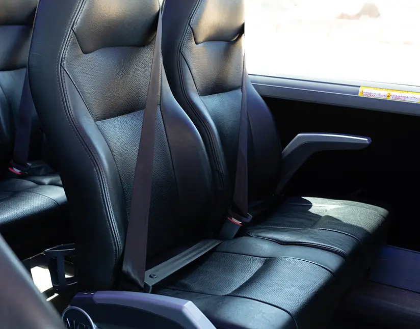 Interior view of black leather coach seats with seat belts.