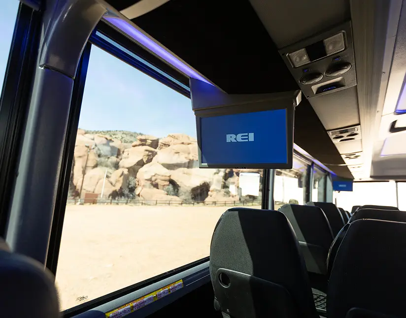 Motorcoach interior with REI screen and large window showing desert landscape.