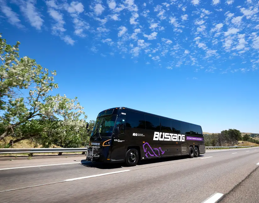 Luxury coach motorcoach from Ace Express Coaches traveling on highway with scenic background.