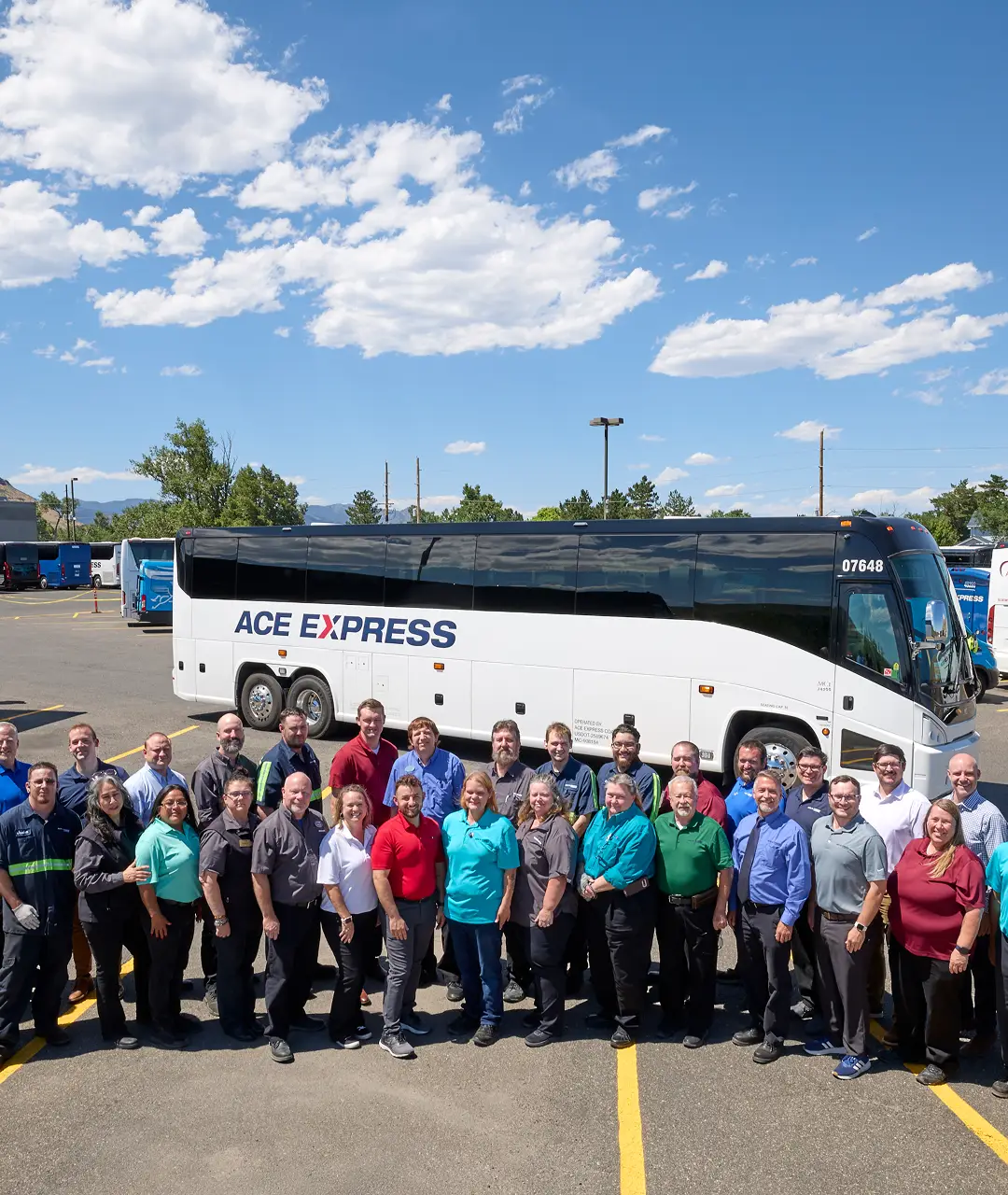 Group photo of Ace Express Coaches staff and motorcoach in parking lot on a sunny day.