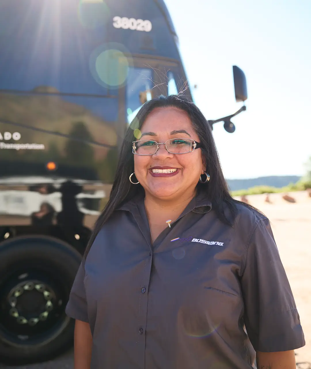 Friendly female motorcoach driver smiling outdoors.