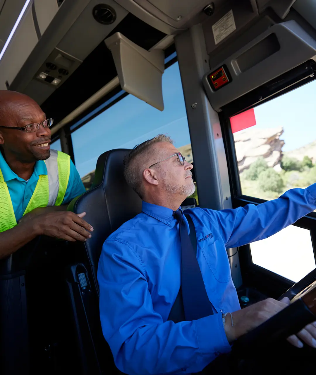 Motorcoach driver and passenger inside the motorcoach, focusing on the road ahead.
