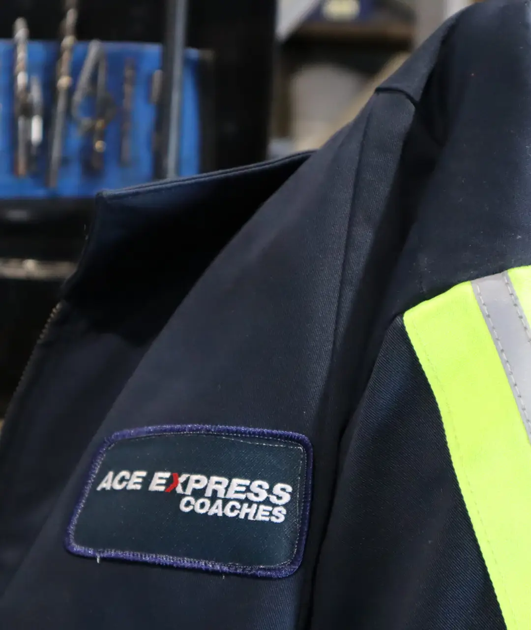 Close-up of ACE Express Coaches uniform with logo patch on dark fabric.