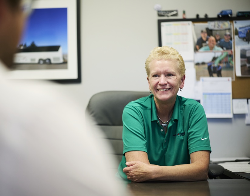 Customer service representative at Ace Express Coaches talking to a customer at her desk